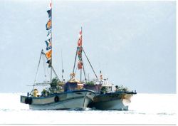 旗などの飾りつけがされた舟が二隻浮かんでいる写真です