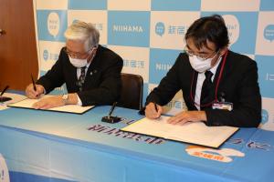 協定書にサインをする石川市長（左）と宮﨑新居浜郵便局長（右）